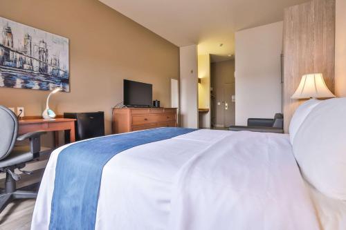 a hotel room with a bed and a desk and a television at Comfort Inn & Suites in Saint-Jérôme