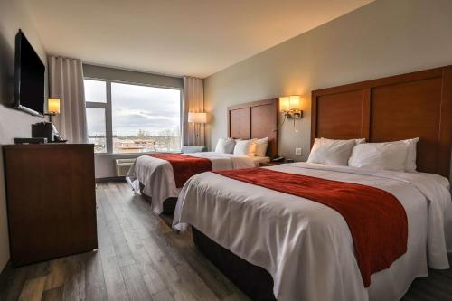 a hotel room with two beds and a large window at Comfort Inn & Suites in Saint-Jérôme