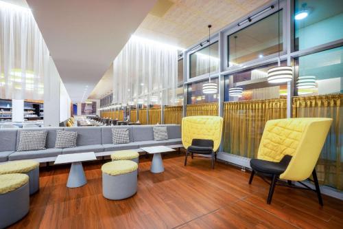 a waiting area with yellow chairs and tables in a store at Hey Lou Hotel Frankfurt Airport in Kelsterbach