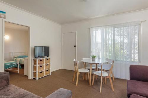 a living room with a table and chairs and a television at Jamaica Holiday Units in Forster