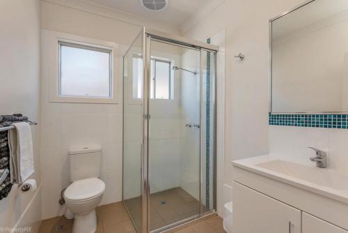 a bathroom with a shower and a toilet and a sink at Jamaica Holiday Units in Forster
