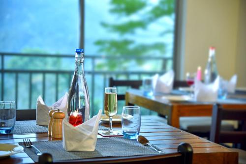 a wooden table with glasses and a bottle of wine at Mistletoe Homestay & Cafe in Munnar