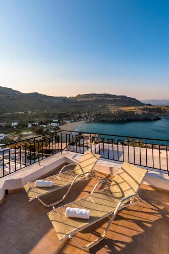 a group of chairs sitting on top of a balcony at Villa Lindos Muse in Líndos