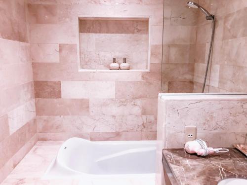 a bathroom with a white tub and a shower at Hikari Guesthouse in Seminyak