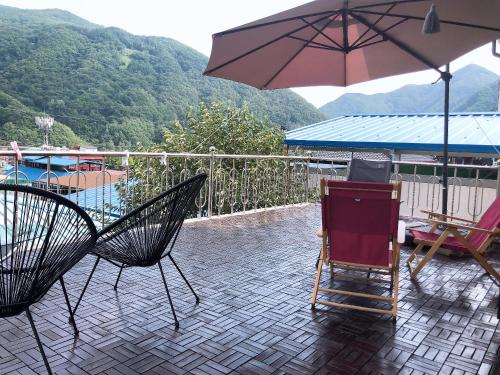 a patio with a table and chairs and an umbrella at Us on Earth Guesthouse in Danyang