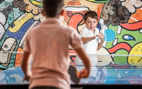 a young boy hitting a ball in front of a wall at Biancaneve Family Hotel in Selva di Val Gardena