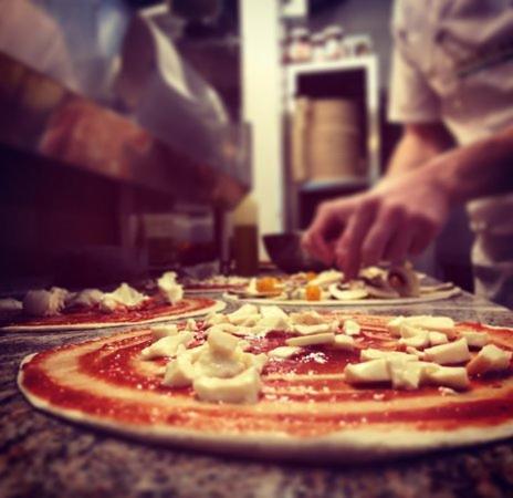 a person making a pizza on a table at B&Bari in Bari