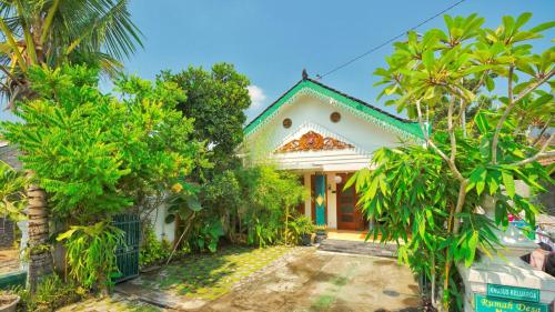 una casa blanca con árboles delante de ella en Rumah Desa Homestay, en Prambanan