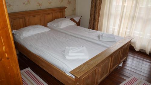 a wooden bed with white sheets and white pillows at Pensiunea Medieval in Predeal