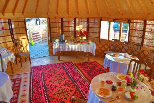 a dining room with tables and chairs and a room with tablesktop at Happy Nomads Yurt Camp & Hostel in Karakol