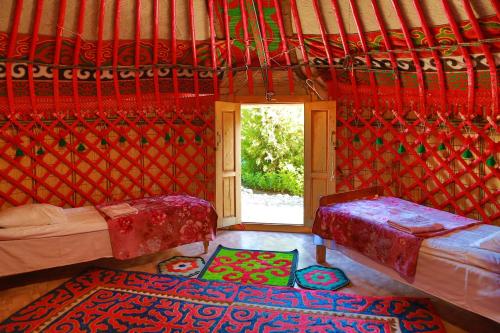 a room with two beds and a window at Happy Nomads Yurt Camp & Hostel in Karakol