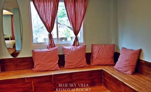 a row of pillows sitting on a bench in front of a window at Blue Sky Villa Khao Yai in Pak Chong
