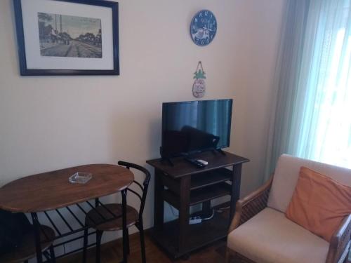 uma sala de estar com uma televisão, uma mesa e uma cadeira em Rozy House Nei Epivates Thessaloniki ( Near the sea) em Néoi Epivátai