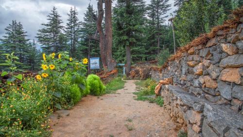 a stone wall and a path with sunflowers at The Wild Trails by Livingstone in Kalpa