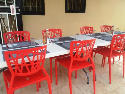a table with red chairs and a white table at Dich Comfort Hotel - Main Branch in Gulu