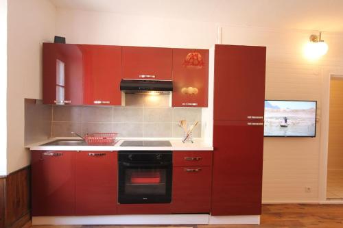 - une cuisine avec des placards rouges et une cuisinière dans l'établissement Gîte L Écrin - Cœur de Riquewihr - 4 personnes, à Riquewihr