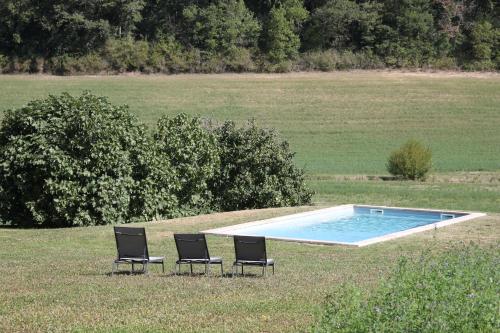 2 chaises et une piscine dans un champ dans l'établissement La Ferme de Saint Christeau, à Auch