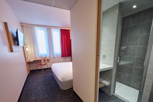 une chambre d'hôtel avec un lit et une douche dans l'établissement Premiere Classe Clermont Ferrand Centre, à Clermont-Ferrand