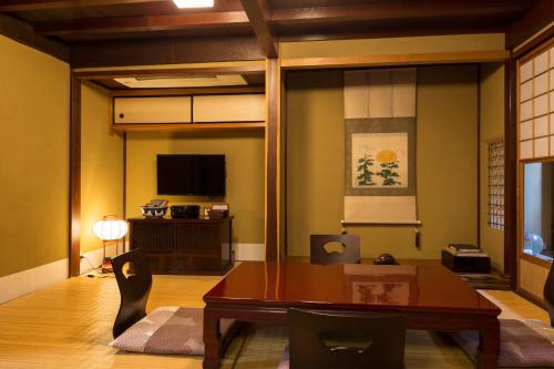 a living room with a table and a television at Machiya Kanazawa Kikunoya in Kanazawa