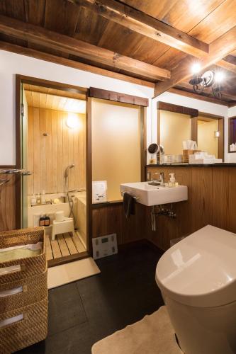 a bathroom with a toilet and a sink and a tub at Machiya Kanazawa Kikunoya in Kanazawa