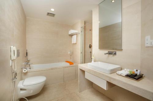 a bathroom with a toilet and a sink and a tub at Ramada by Wyndham Kathmandu Dhumbarahi in Kathmandu