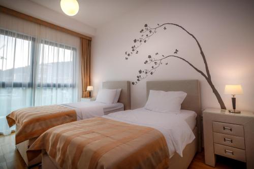 a bedroom with two beds and a tree branch on the wall at Luxury Budva Center Apartments in Budva