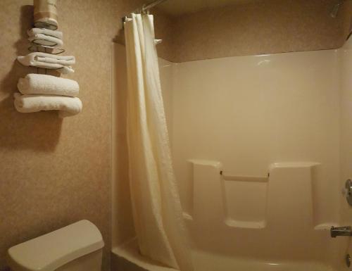 a bathroom with a shower and a toilet and towels at Atrium Inn & Suites in Galloway