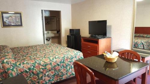 a hotel room with a bed and a tv and a table at Atrium Inn & Suites in Galloway