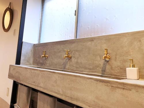 a bathroom sink with gold faucets and a mirror at Cactus Inn in Miyazaki