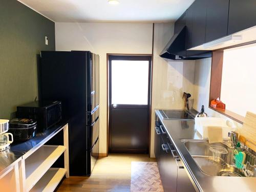 a kitchen with a sink and a black refrigerator at Cactus Inn in Miyazaki