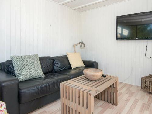 a living room with a black leather couch and a table at 4 person holiday home in Fan in Fanø