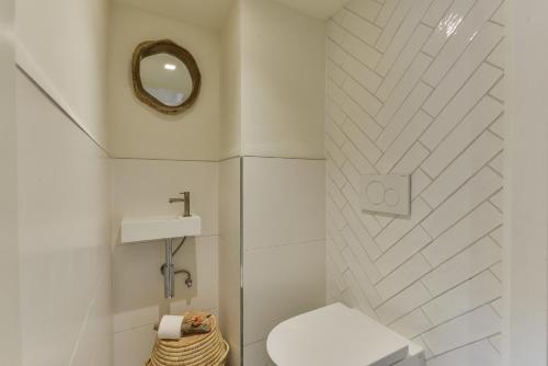 a white bathroom with a toilet and a mirror at Luxury Beach Studio Zandvoort in Zandvoort