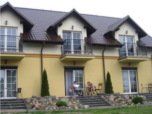 a man and woman sitting at a table in front of a house at Paradise in Charzykowy