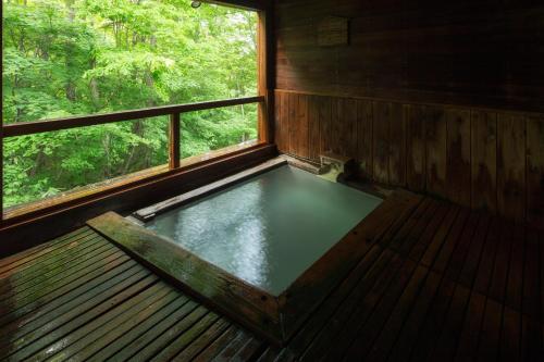an empty tub in a room with a window at Takamiya Hotel Jurin in Zao Onsen