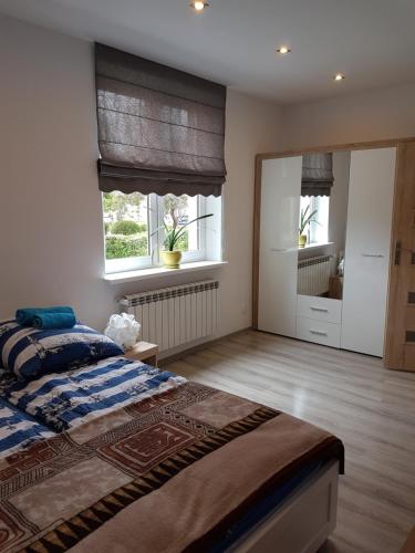 a bedroom with a large bed and two windows at Apartament przy plaży in Mikołajki