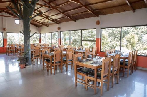 um restaurante com mesas e cadeiras de madeira e janelas em Himalayan Deurali Resort em Pokhara