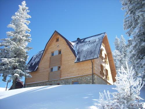 a large wooden house with snow on the ground at Apartmani Marija in Jahorina