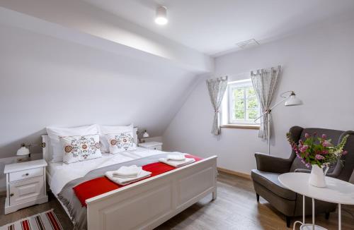 1 dormitorio blanco con 1 cama y 1 silla en Dom Nad Wodospadem pod Śnieżnymi Kotłami, en Jelenia Góra-Jagniątków
