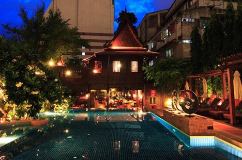 a building with a swimming pool in a city at night at Rose Hotel in Bangkok