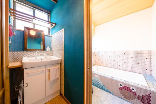Łazienka z niebieskimi ścianami, umywalką i wanną w obiekcie 富士山金魚 Fujisan Kingyo w mieście Fujikawaguchiko
