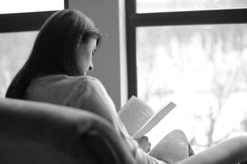 a woman sitting on a couch reading a book at Vardeni Guesthouse in Hrazdan
