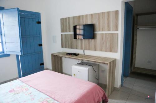 a bedroom with a bed and a desk with a tv at Rafa's Pousada Encantos de Minas in Três Corações