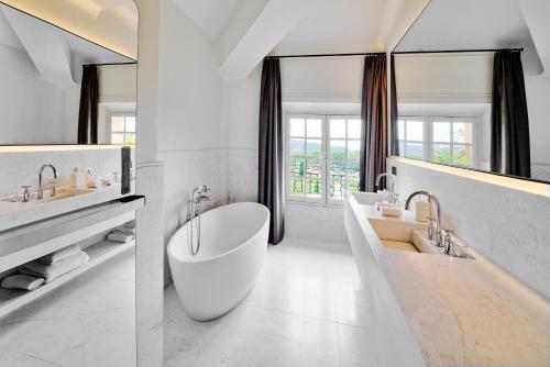 La salle de bains blanche est pourvue de 2 lavabos et d'une baignoire. dans l'établissement Château de la Gaude, à Aix-en-Provence