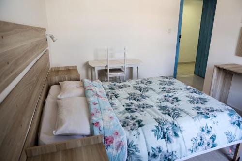 a bedroom with a bed with a blue and white blanket at Rafa's Pousada Encantos de Minas in Três Corações
