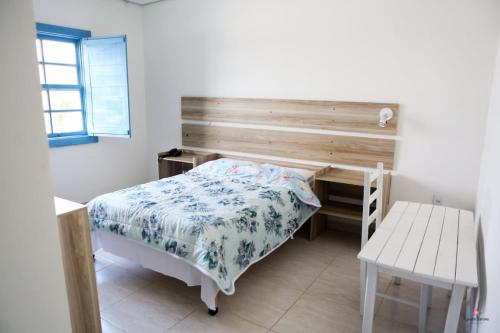 a bedroom with a bed and a wooden headboard at Rafa's Pousada Encantos de Minas in Três Corações