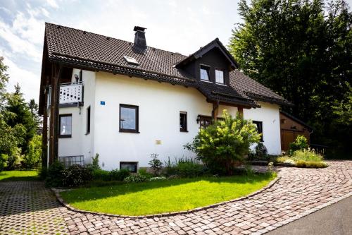a white house with a black roof and a brick driveway at Steinbachblick in Steinbach am Wald