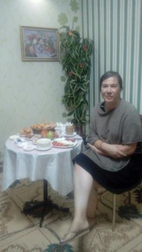 a woman sitting in a chair in front of a table at Family Guest house - Friends-J in Nukus