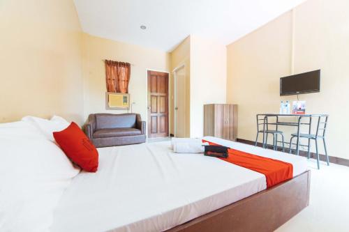 a bedroom with a large white bed and a chair at RedDoorz @ Lagao General Santos in General Santos