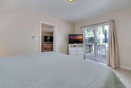 a white bedroom with a large bed and a television at Elderberry in Siesta Key