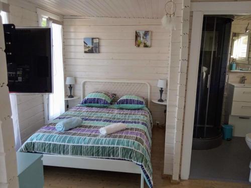 ein Schlafzimmer mit einem Bett mit Kissen und einem TV in der Unterkunft AGREABLE PETIT CHALET in Camarsac